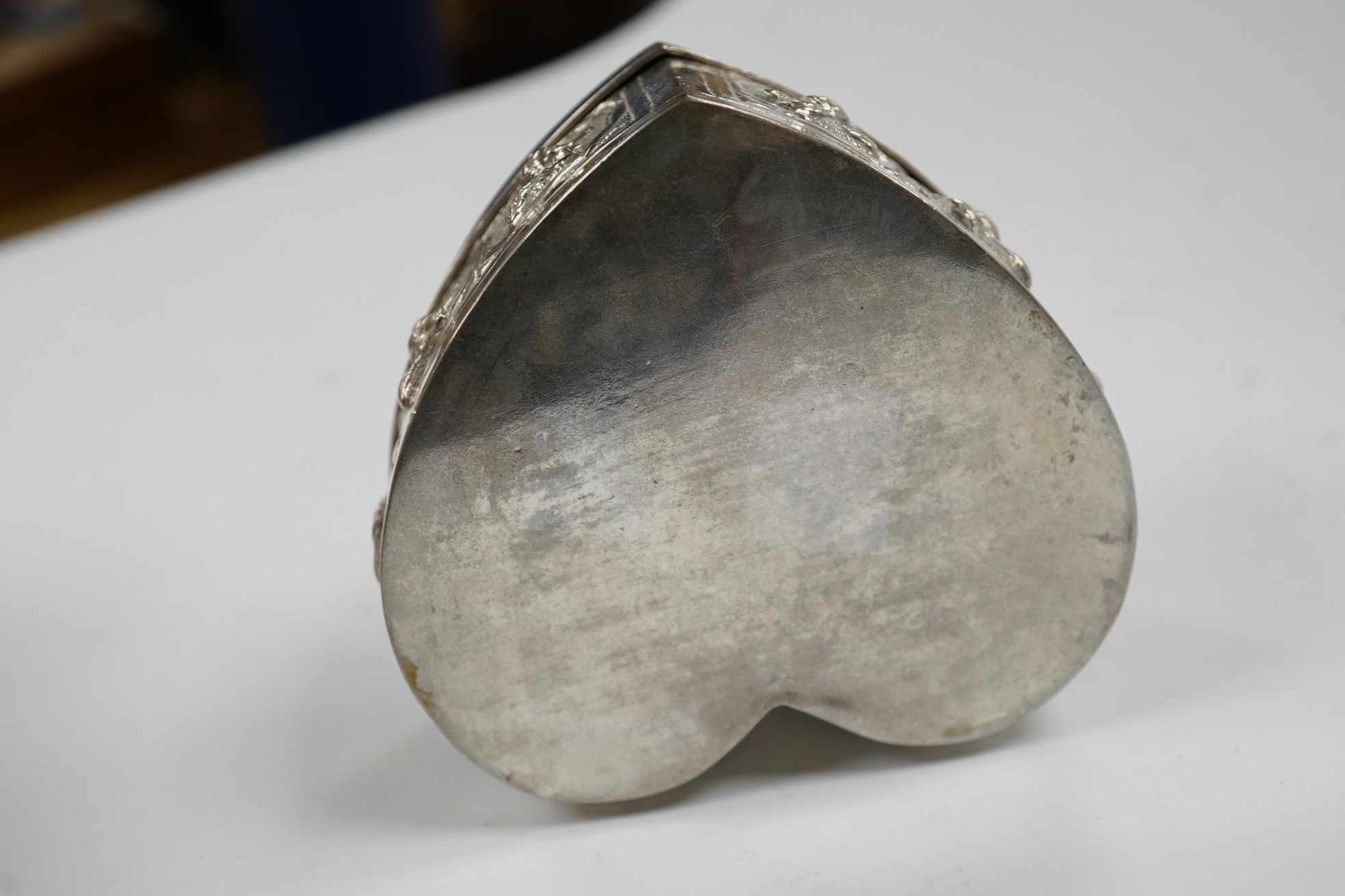 An Indian embossed white metal heart shaped trinket box and cover, width 85mm, 120 grams. Condition - fair